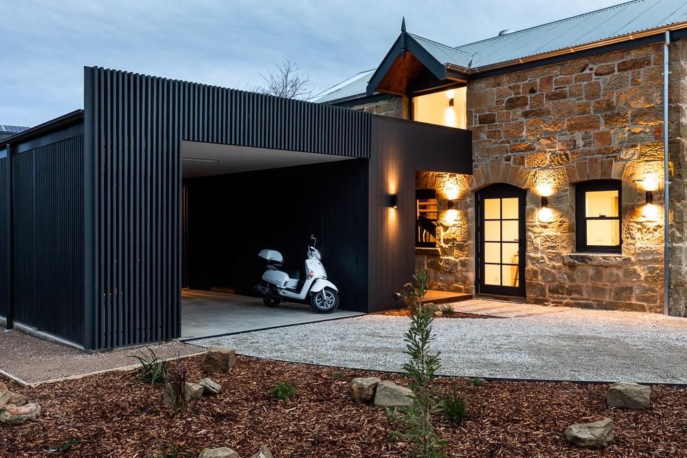 The garage and entrance of a newly built house with warm, inviting lighting at the front door and windows